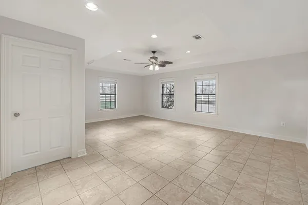 an empty room with windows and ceiling fan