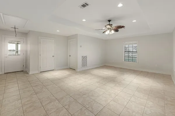 an empty room with chandelier fan and windows