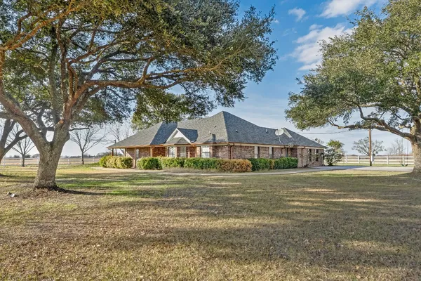 a front view of a house with a garden and trees