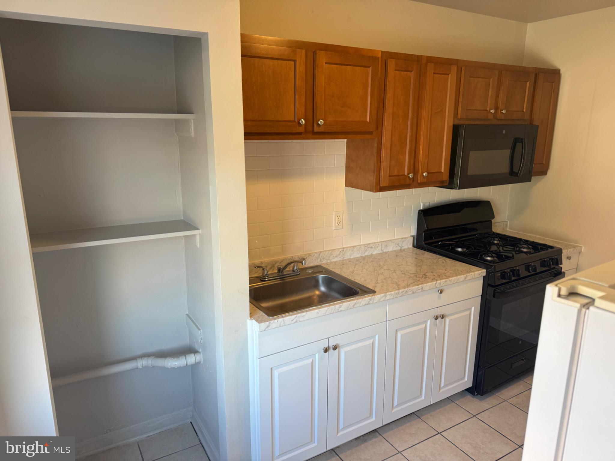 2803 Edison Highway, Unit 2 Baltimore, MD 21213 - Photo 3 of 11 a kitchen with a refrigerator and a stove top oven