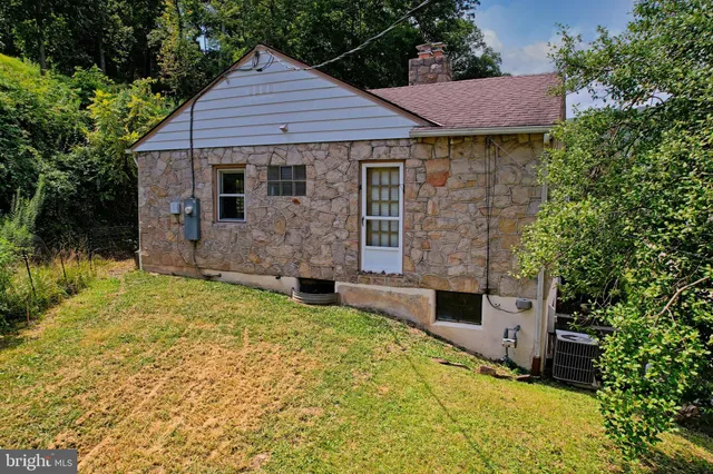 a backyard of a house with table and chairs under an umbrella