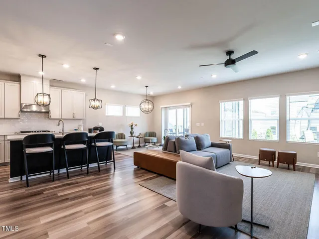 a living room with furniture kitchen view and a large window