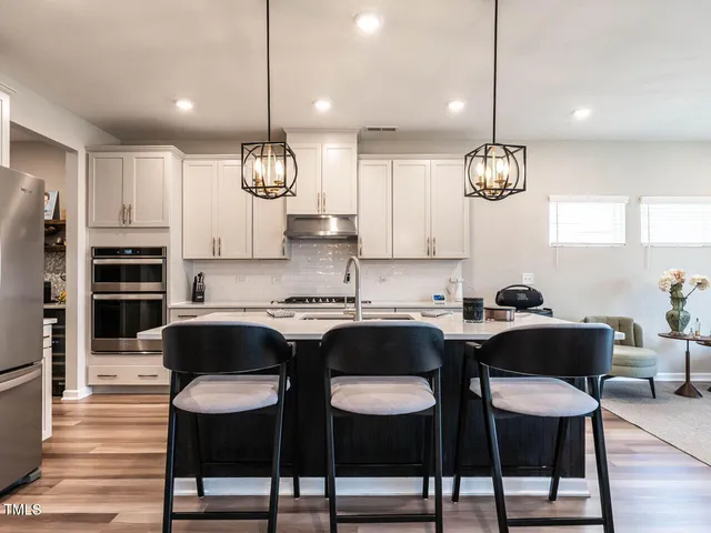 a kitchen with granite countertop a table chairs stove and microwave