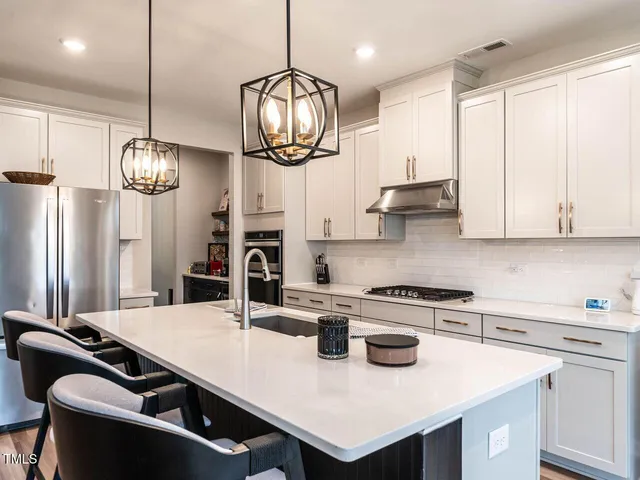 a kitchen with kitchen island stainless steel appliances a table chairs and a chandelier