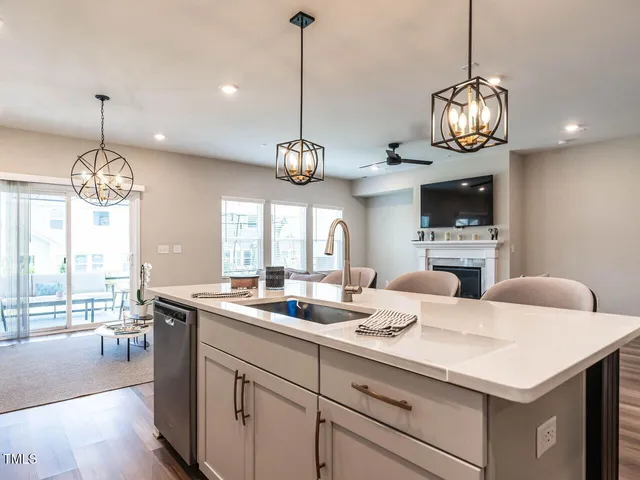 a very nice looking dining room with kitchen island furniture a large window and a chandelier