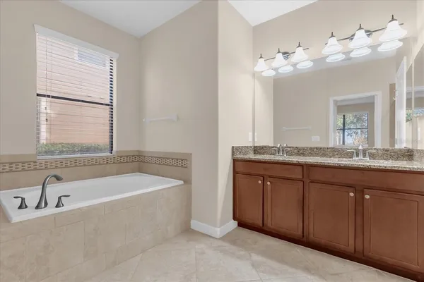 a bathroom with a granite countertop bathtub a sink and a large mirror