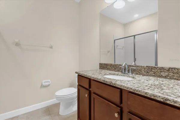 a bathroom with a granite countertop sink a toilet and a mirror