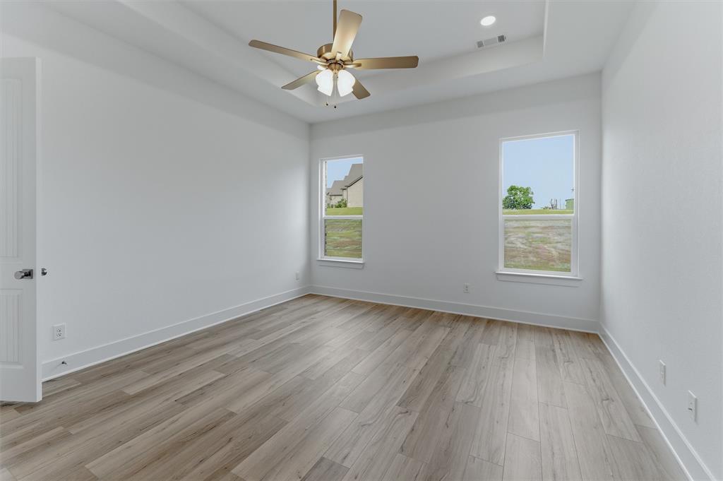906 Perrin Lane Van Alstyne, TX 75495 - Photo 19 of 30 an empty room with wooden floor chandelier fan and windows
