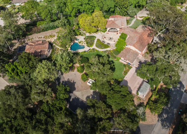 an aerial view of residential house with outdoor space and trees all around