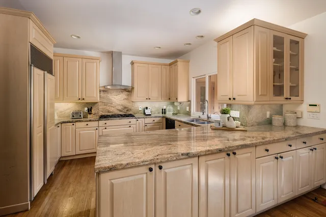 a kitchen with kitchen island granite countertop a sink cabinets and stainless steel appliances
