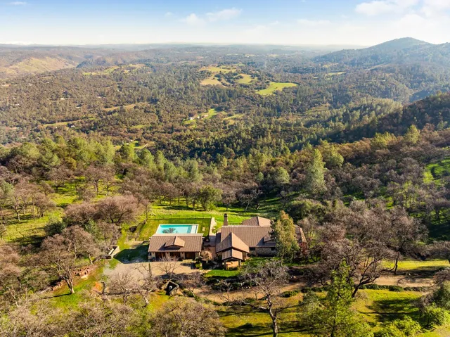 an aerial view of residential houses with outdoor space and trees