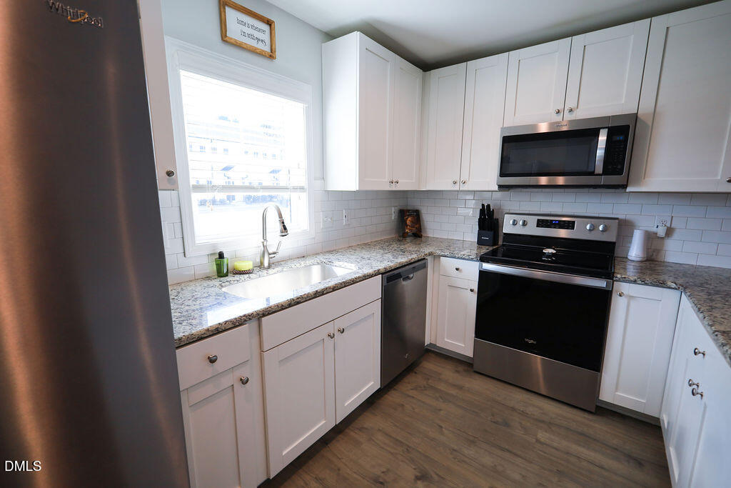230 South Raleigh Street Angier, NC 27501 - Photo 7 of 38 a kitchen with granite countertop white cabinets and black stainless steel appliances