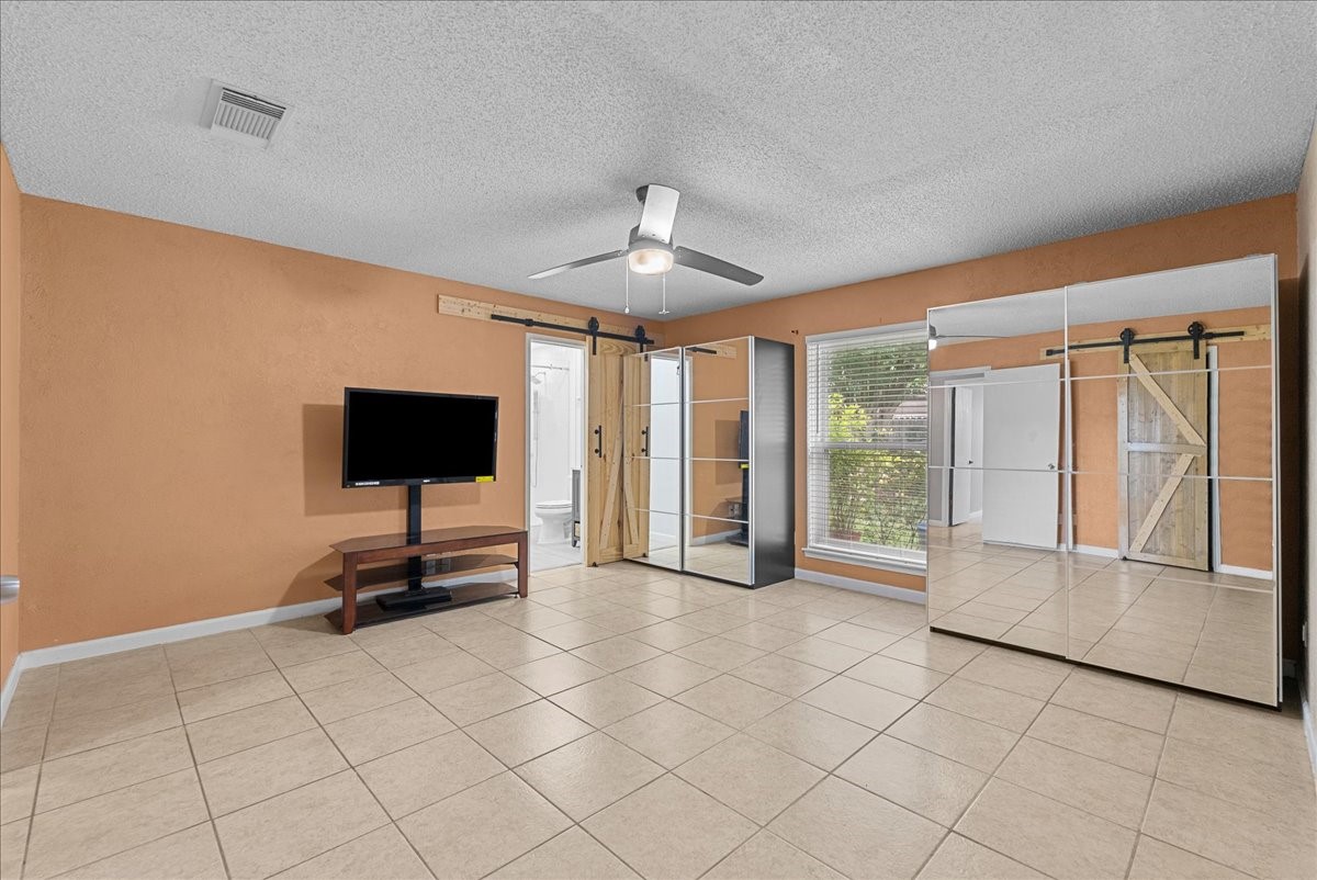 883 Silverpines Road Houston, TX 77062 - Photo 17 of 38 Bright Primary bedroom with tiled floors, warm peach walls, and a ceiling fan and an abundance of natural light.
An en-suite bathroom with mirrored closets .