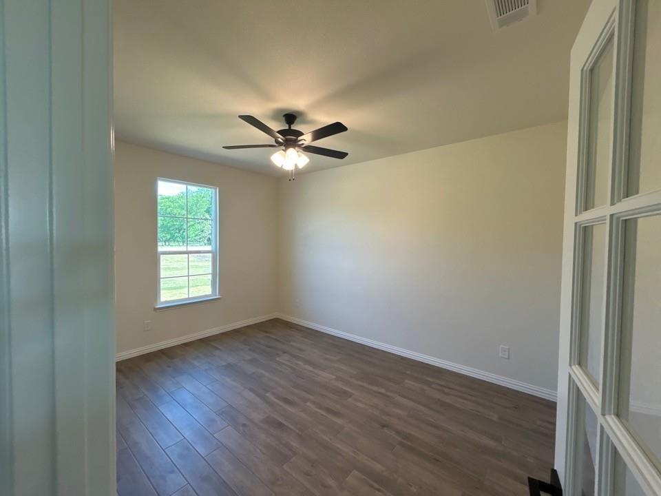 8813 County Road 623 Blue Ridge, TX 75424 - Photo 4 of 19 Versatile room featuring wood-finish flooring, a single window, and a ceiling fan with integrated lighting