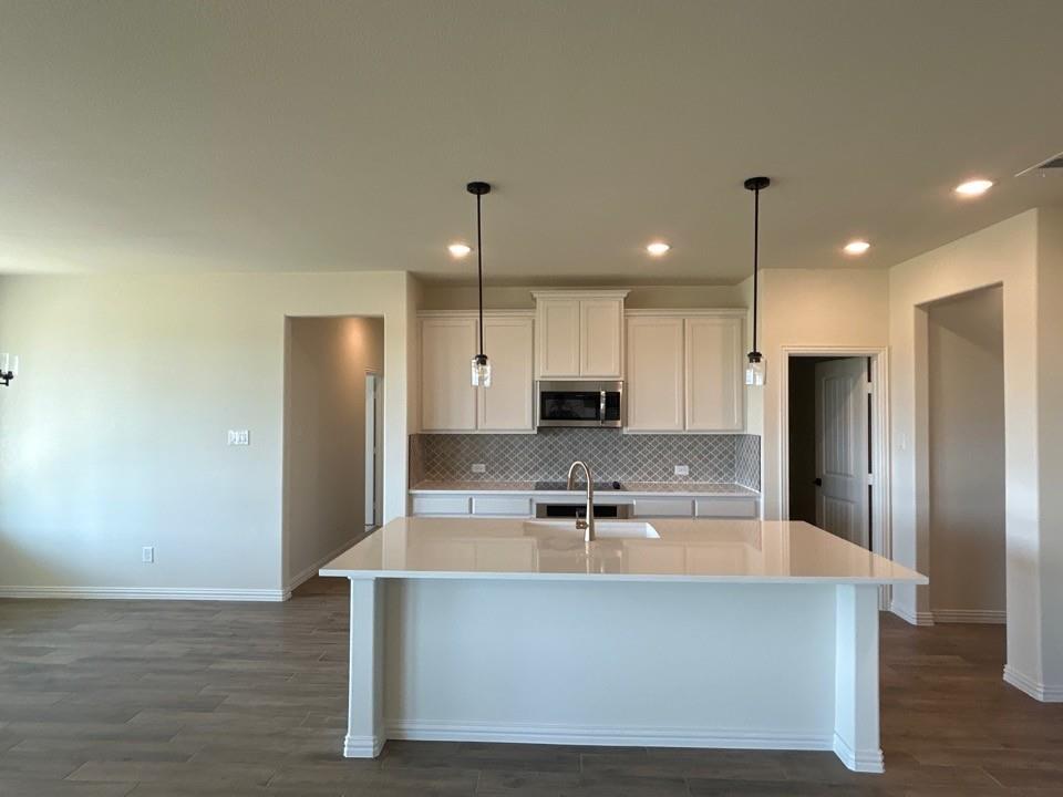8813 County Road 623 Blue Ridge, TX 75424 - Photo 6 of 19 Kitchen featuring a large island, white cabinetry, integrated microwave, mosaic tile backsplash, and stainless steel sink with a gooseneck faucet