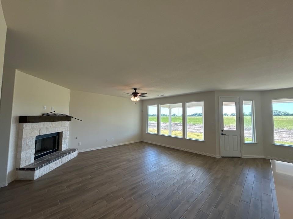 8813 County Road 623 Blue Ridge, TX 75424 - Photo 7 of 19 Spacious interior featuring wood-finish flooring, a stone-clad fireplace with a dark wood mantel, a ceiling fan, and multiple windows providing natural light