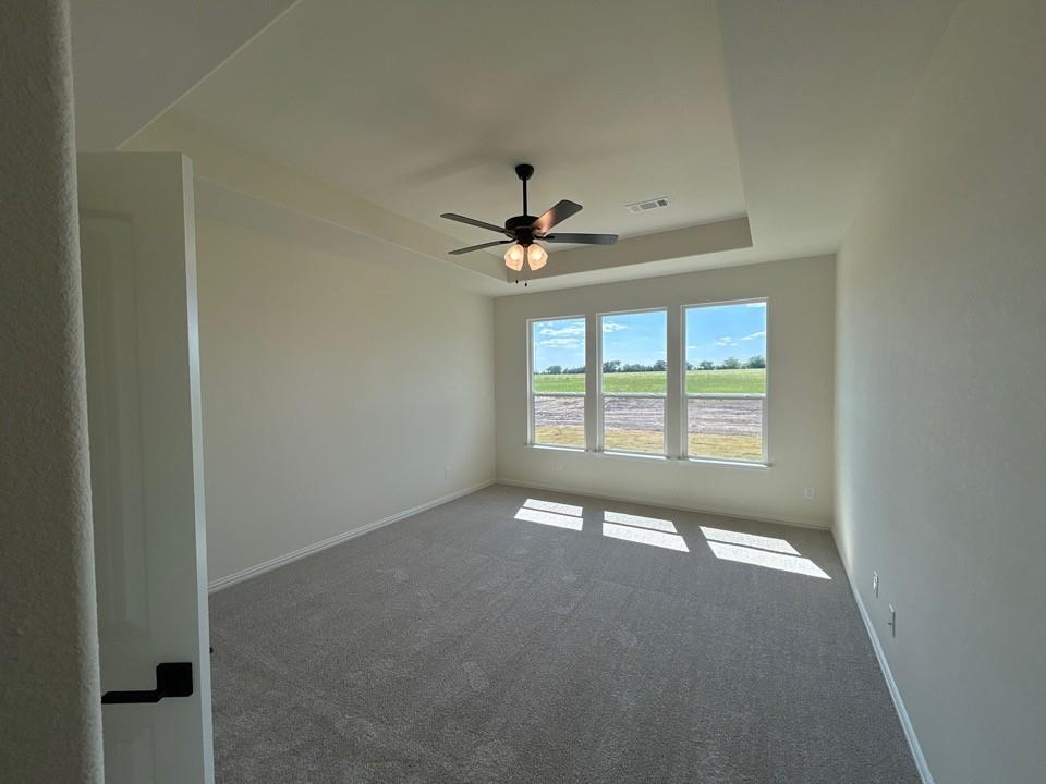 8813 County Road 623 Blue Ridge, TX 75424 - Photo 10 of 19 Spacious room featuring gray textured carpeting, a tray ceiling, and a ceiling fan with light fixture
