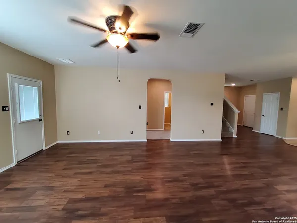 a view of an empty room with a ceiling fan and window