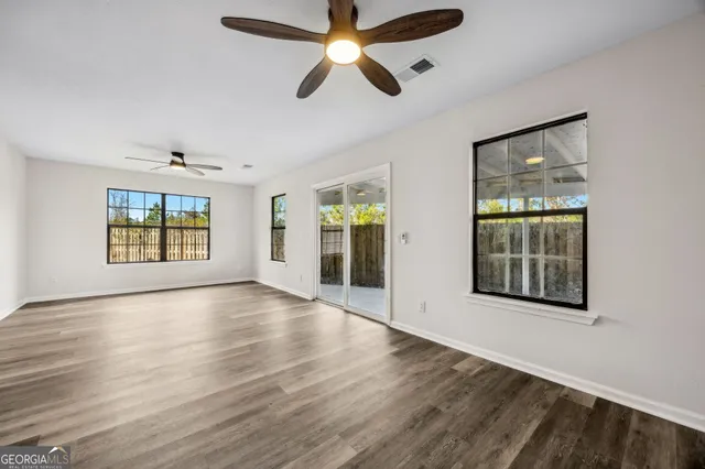 a view of an empty room with wooden floor and window