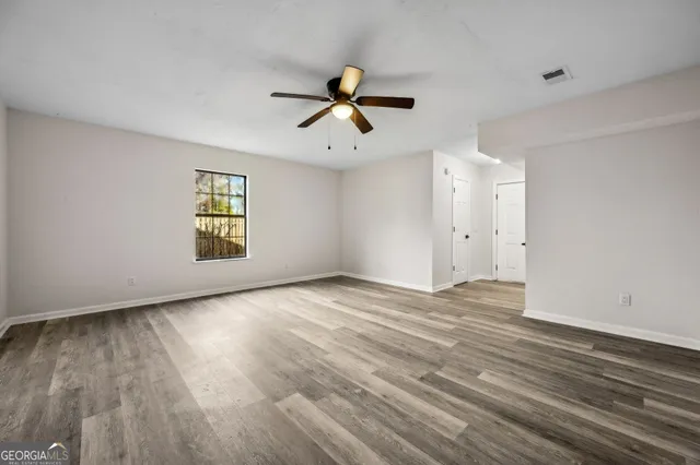 a view of an empty room with a window and wooden floor