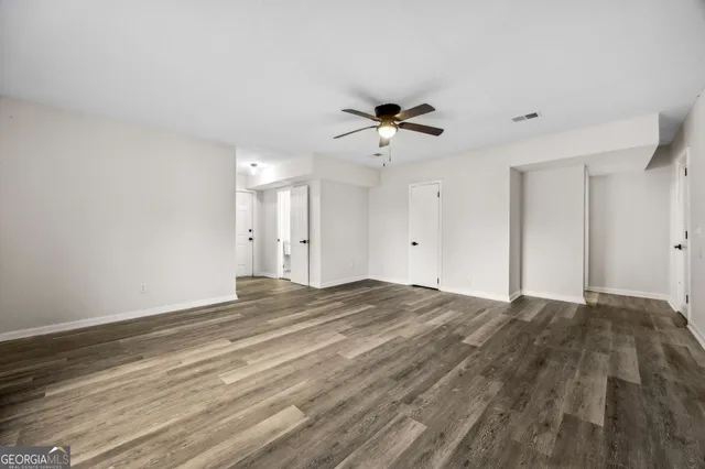 a view of an empty room with wooden floor and a window