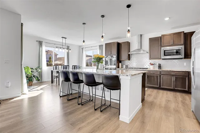 a kitchen with stainless steel appliances a dining table chairs microwave and sink