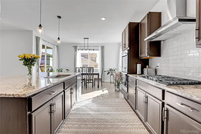 a kitchen with stainless steel appliances granite countertop a sink a stove and a wooden floors