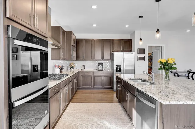 a large kitchen with stainless steel appliances kitchen island granite countertop a stove a sink and a refrigerator