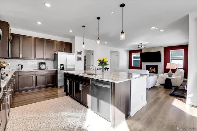 a kitchen with stainless steel appliances kitchen island granite countertop a sink and a refrigerator
