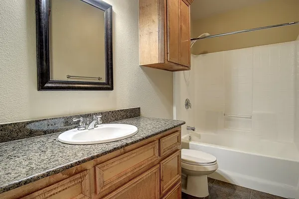 a bathroom with a granite countertop sink toilet and mirror