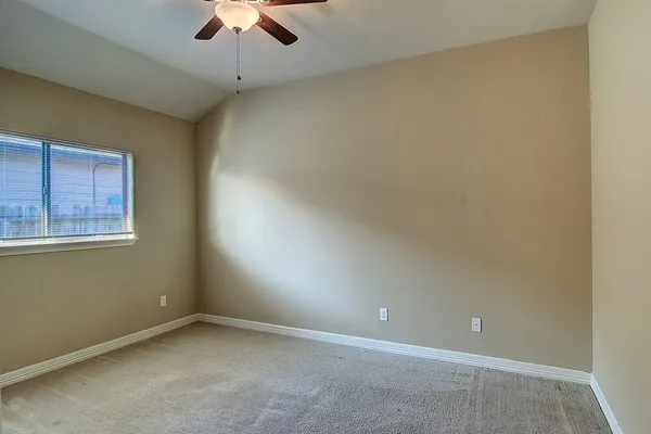 an empty room with a ceiling fan and window