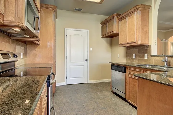 a kitchen with granite countertop a sink a stove and cabinets