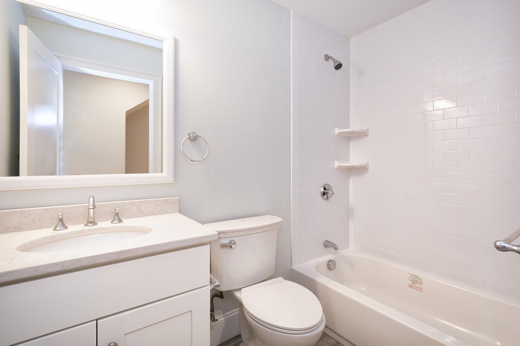 95 First Parish Road, Unit 1 Scituate, MA 02066 - Photo 17 of 24 a bathroom with a toilet a sink a mirror a bathtub and vanity