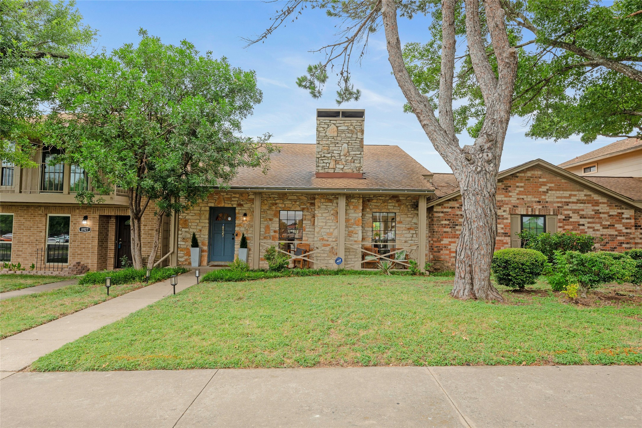View of front of home with a front yard, roof with shingles, and brick siding