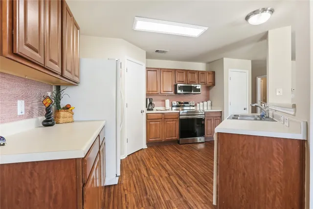 a kitchen with a sink dishwasher a stove and a refrigerator with wooden floor
