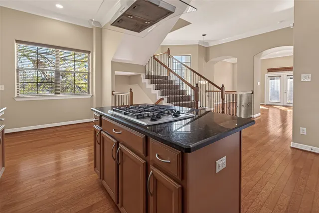 a kitchen with granite countertop stainless steel appliances a refrigerator cabinets and wooden floor