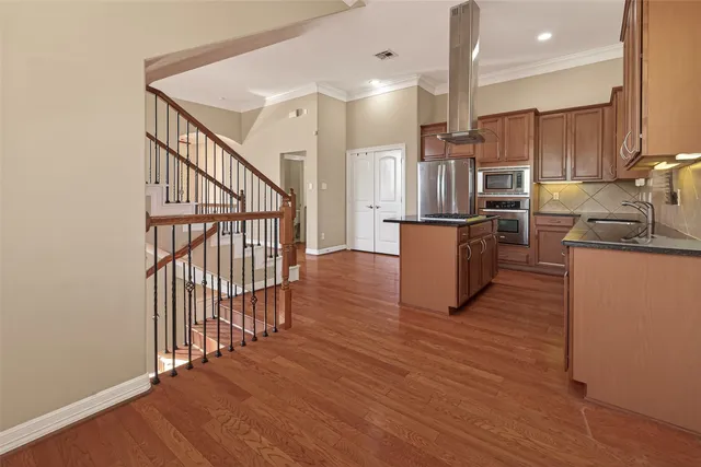 a kitchen with stainless steel appliances granite countertop a refrigerator a sink dishwasher a stove and white cabinets with wooden floor