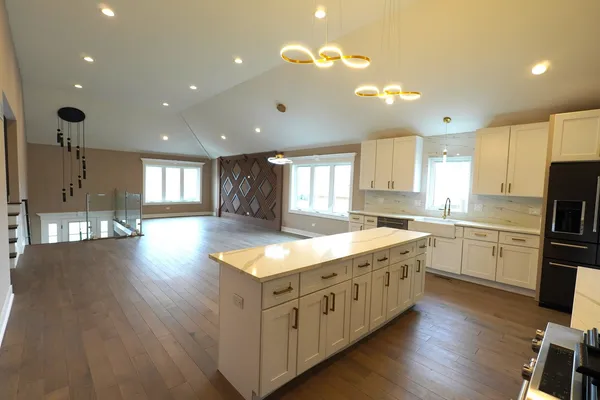 a kitchen with stainless steel appliances granite countertop a stove top oven a sink dishwasher and a refrigerator with wooden floor