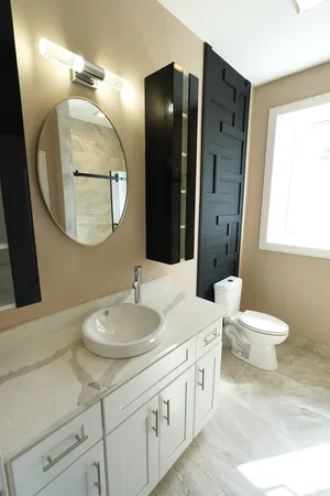 a bathroom with a granite countertop toilet sink and mirror