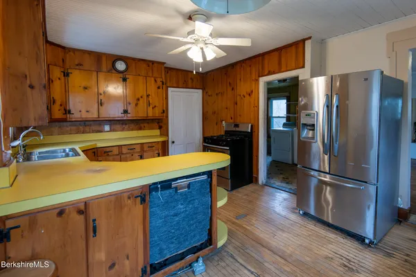 a kitchen with stainless steel appliances wooden floor and a refrigerator