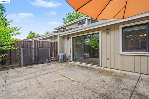 a backyard of a house with lawn chairs and an umbrella