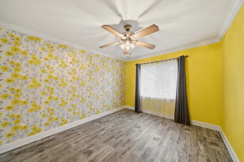 an empty room with wooden floor and a ceiling fan