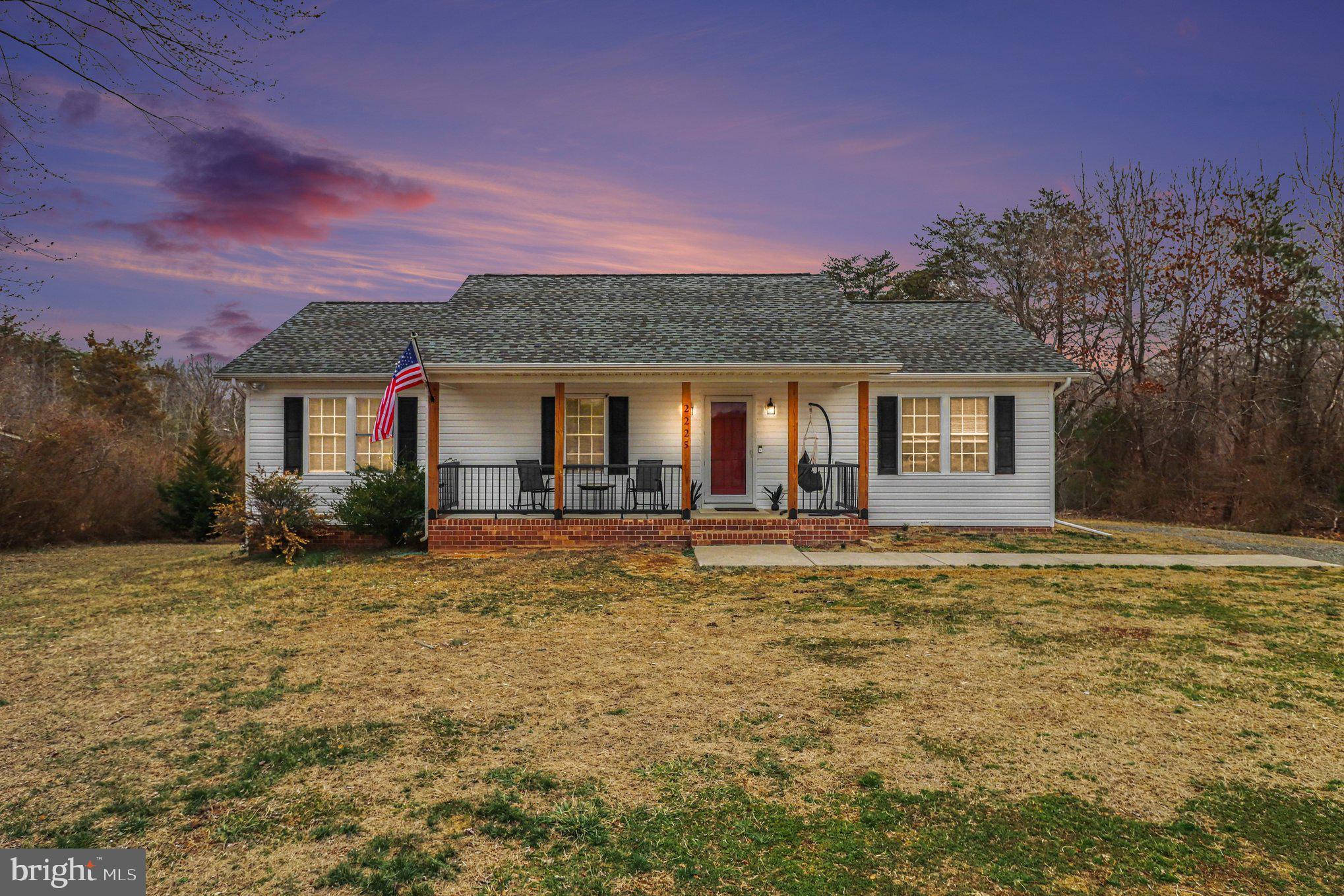 a front view of house with yard and trees in the background