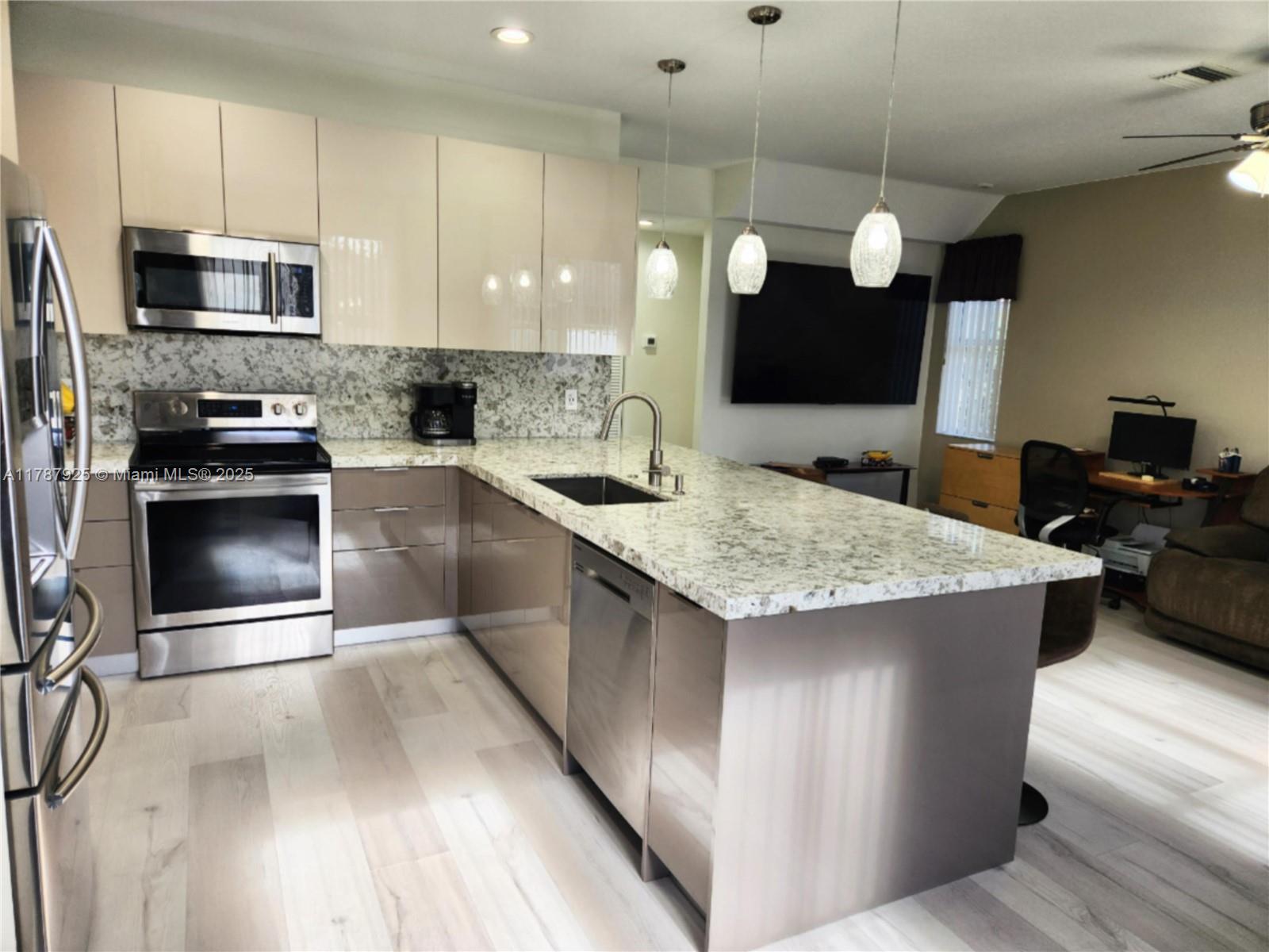785 Falling Water Road Weston, FL 33326 - Photo 15 of 45 a kitchen with kitchen island granite countertop a stove top oven a sink a counter space and cabinets