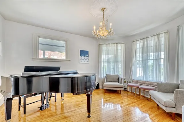 a dining room with wooden floor a chandelier a wooden table and chairs