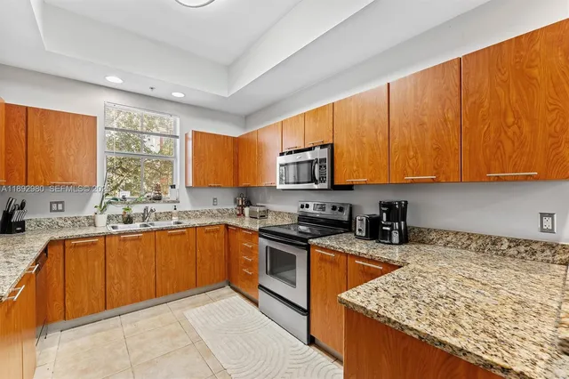 a kitchen with stainless steel appliances granite countertop wooden cabinets a sink dishwasher and a stove top oven with wooden floor