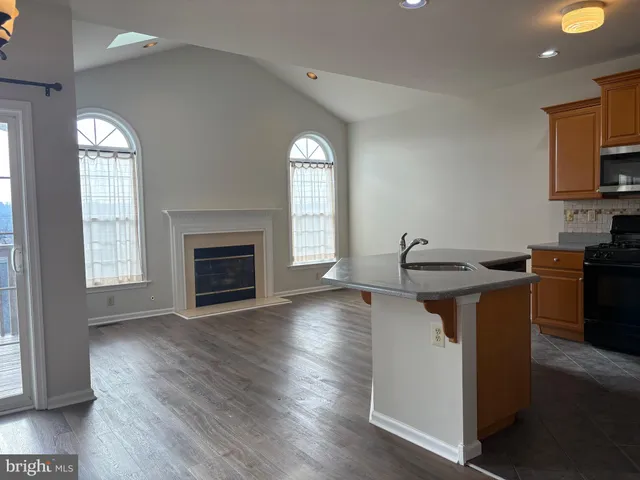 a kitchen with a sink and a stove top oven with wooden floor