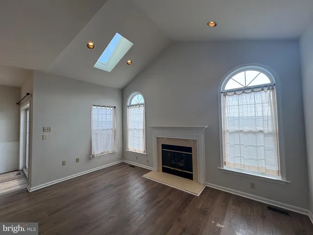 an empty room with windows fireplace and wooden floor