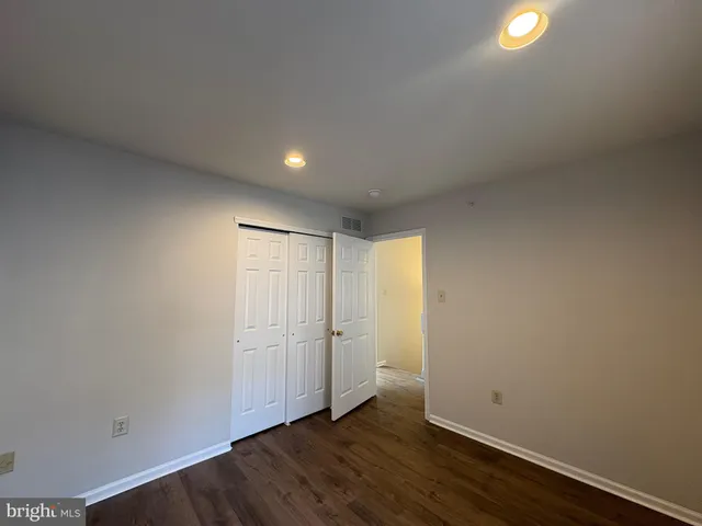 a view of an empty room with wooden floor and windows
