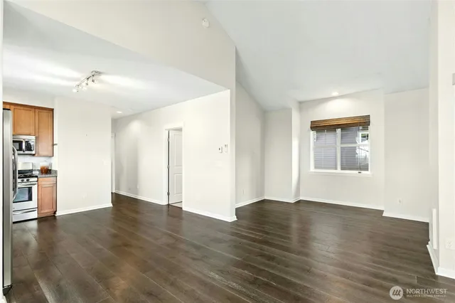 a view of an empty room with window and wooden floor
